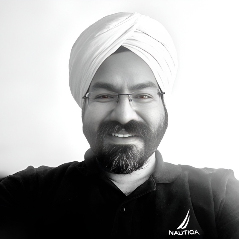 Portrait of Amandeep Singh, smiling, in a white turban and glasses